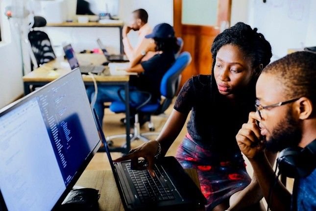 Team members in an office setting, working in front of a desktop computer monitor, streamlining proposal management tools with automation